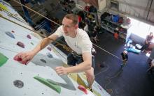 Smiling climber 5m from floor with belayer holding rope in background